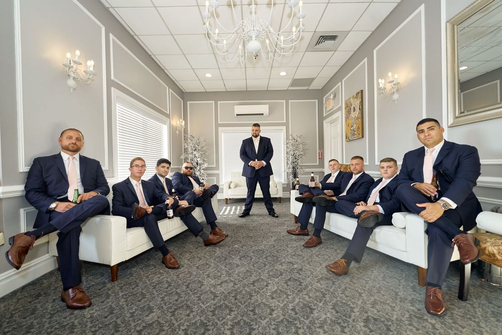 Formal group seated in an elegant room with chandelier and white decor.