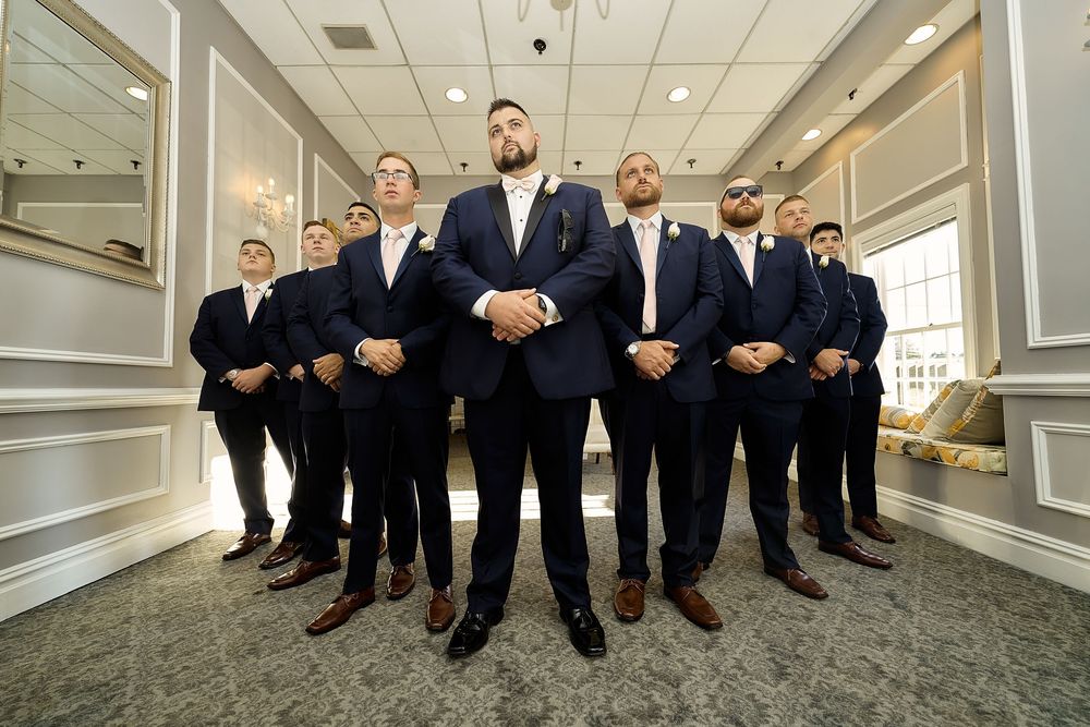 Group in formal attire posed together in an elegant hallway.