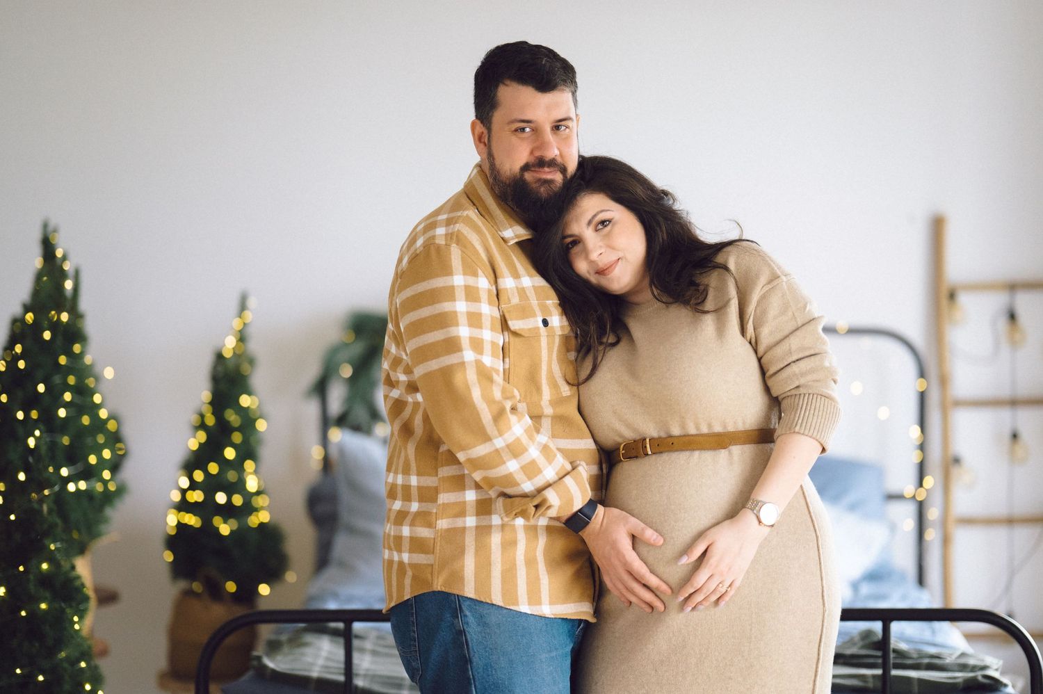 Heartwarming family moment with couple snuggling in living room with soft Christmas tree lights in background.