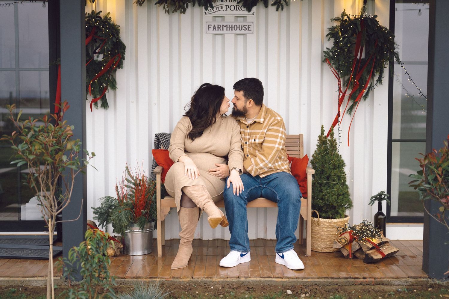 Two people sitting together on a festive porch with Christmas wreaths and seasonal decorations.
