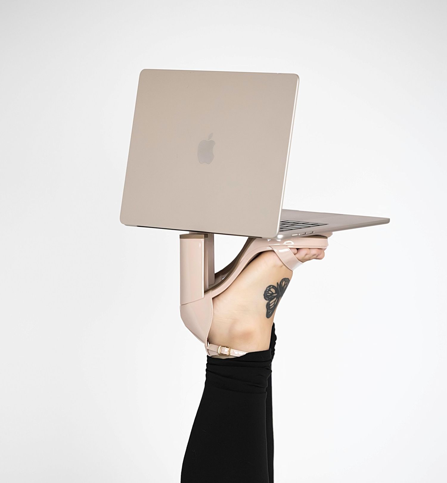 Plus-size woman in beige ribbed top and black leggings holding a white notebook, posing in nude heels.