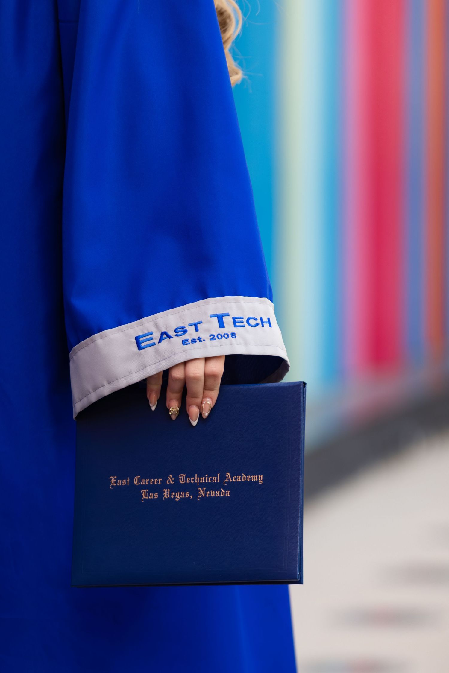 East Tech graduate in blue gown holds diploma from East Career & Technical Academy, Las Vegas, Nevada.