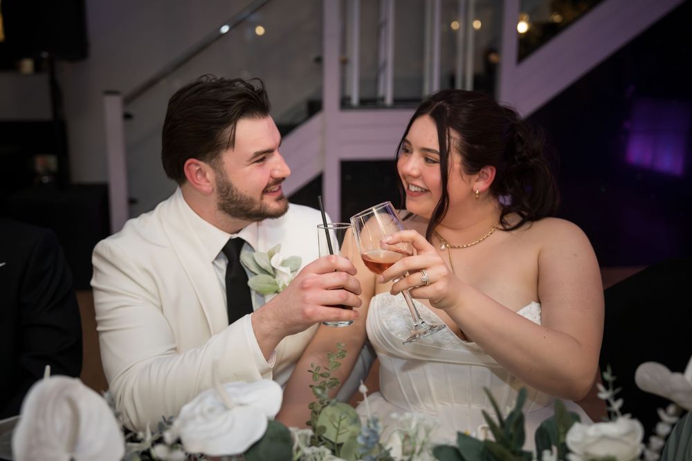 Newlyweds share a toast at their wedding reception table.