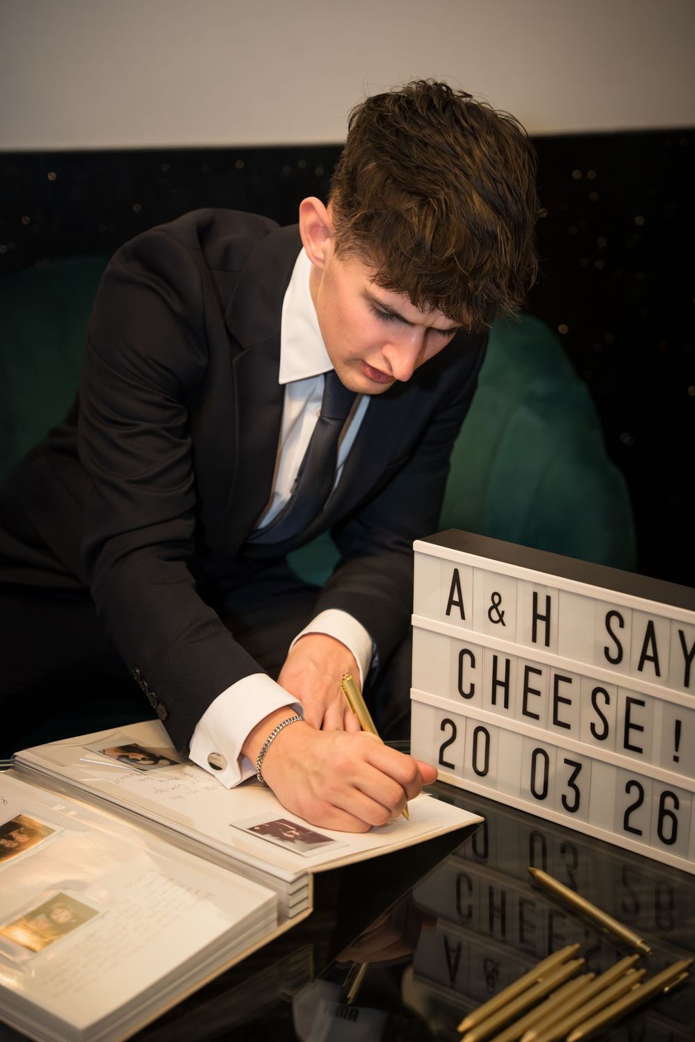 A person in a suit writes on a white board with illuminated letters in a dark setting.