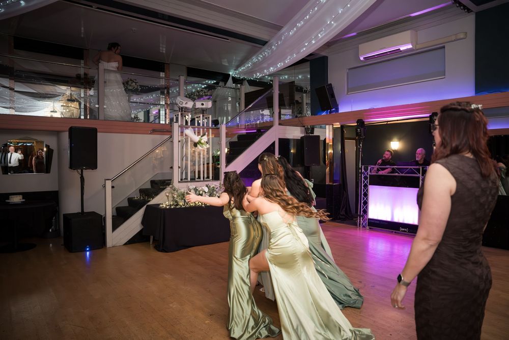 People dancing and socializing in a modern venue with purple mood lighting and white decor elements.