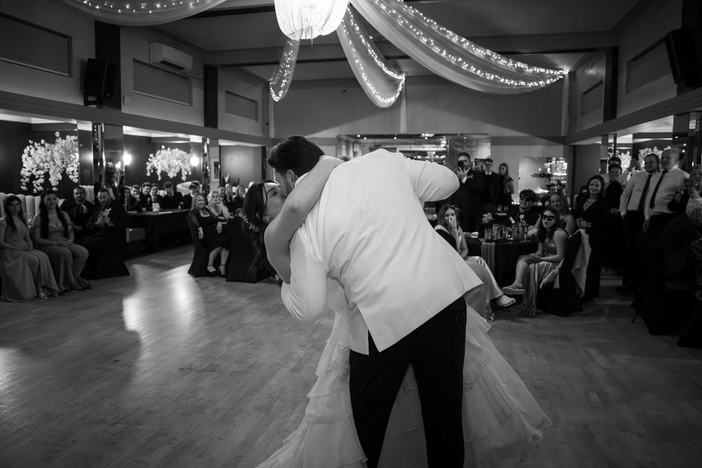 Black and white photo of a couple sharing their first dance at a wedding reception.