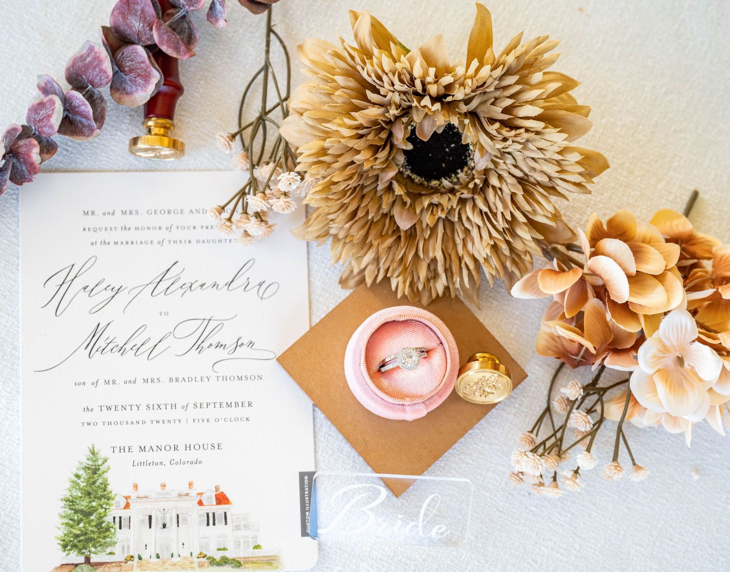 Wedding invitation with watercolor illustration and dried flowers on light textured background.