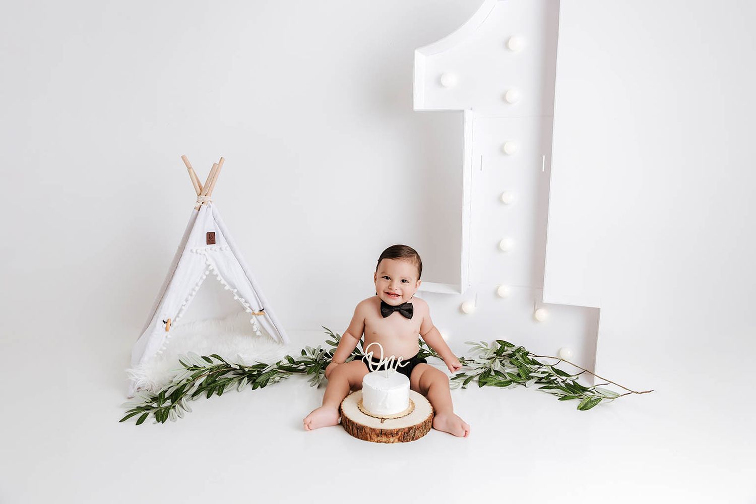 A baby boy celebrates his first birthday with a cake smash in a white studio by Temescal Valley baby photographer.