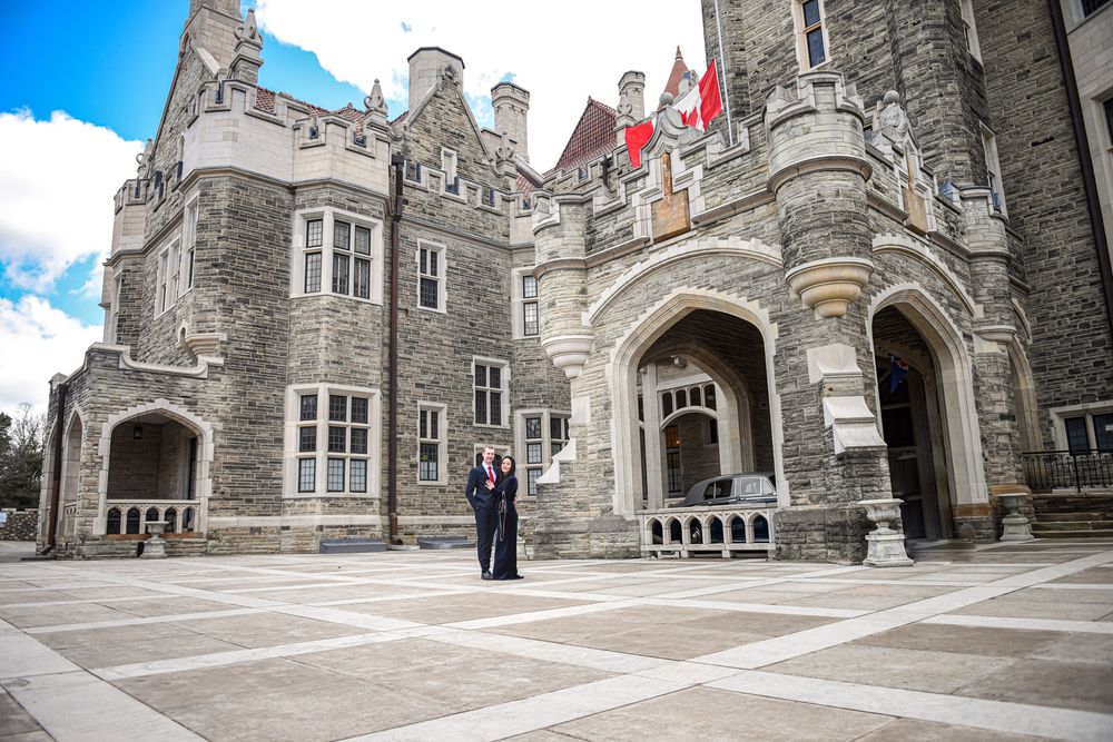 Couple standing before the grand Gothic stone facade of Casa Loma castle in Toronto.