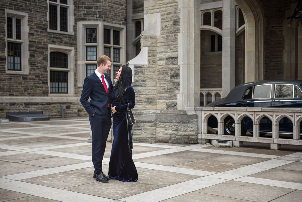Elegant couple sharing a romantic moment in a castle courtyard with a vintage black car in the background.