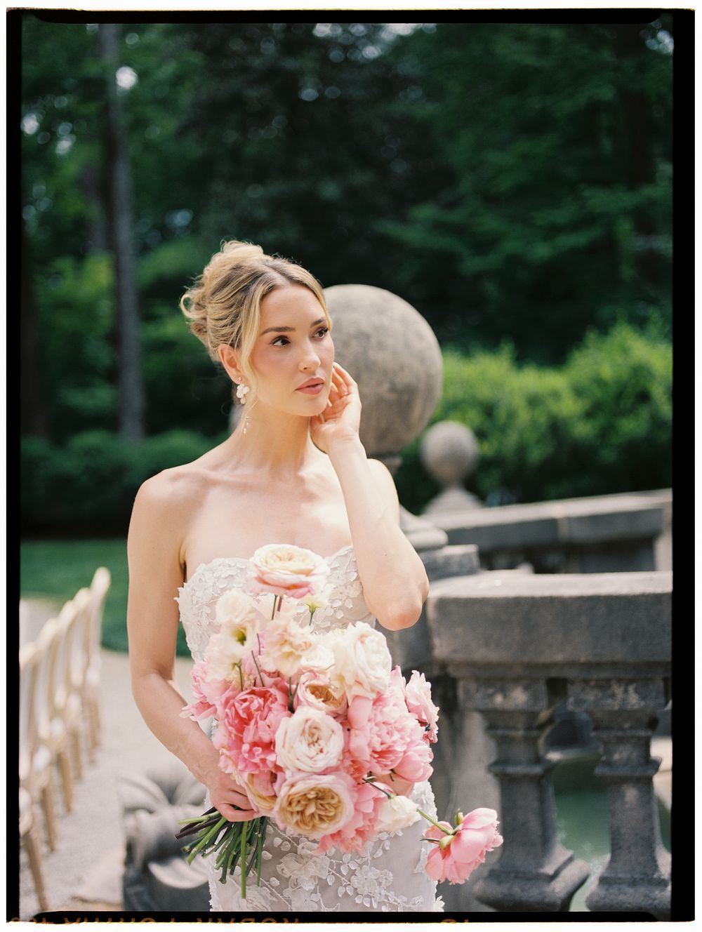 Elegant bride in beaded gown holds lush pink peony bouquet in a romantic garden setting.