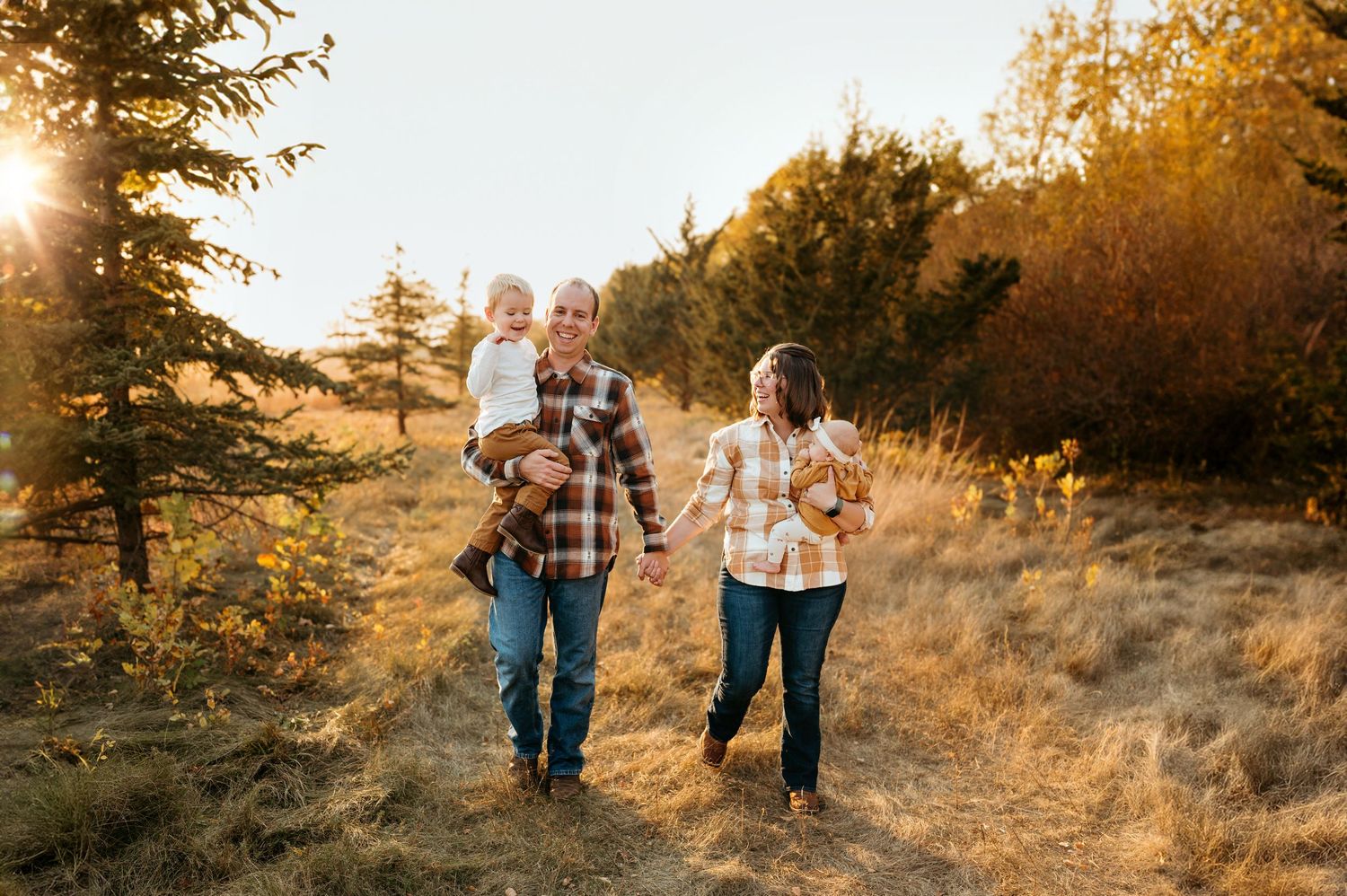 Outdoor family session in golden light with parents, young children, tall grass and warm film-inspired photography in Brookings SD.