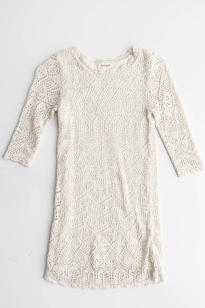 Cream colored crochet lace mini dress with 3/4 sleeves and intricate diamond pattern detailing, laid flat.