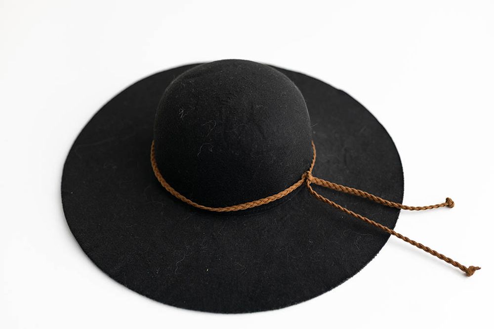 Classic wide-brim black felt floppy hat with braided brown leather band, displayed on white background.