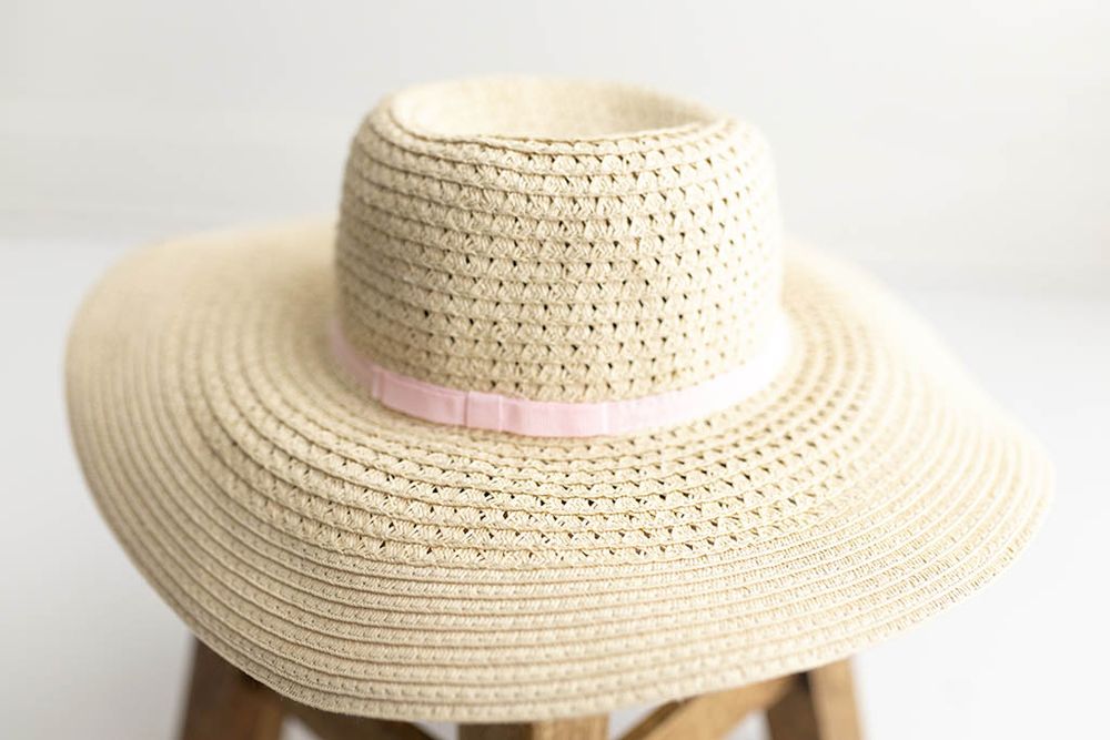 Beige woven straw wide-brim sun hat with pink ribbon band for child photoshoot in Menifee.