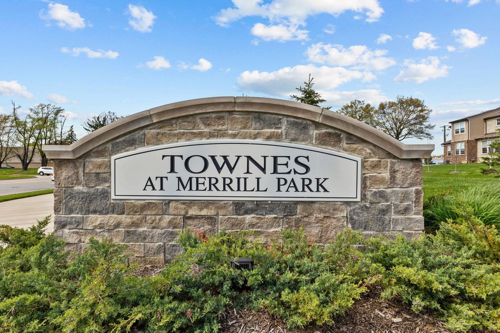 Stone entrance sign for Townes at Merrill Park residential community surrounded by landscaping.