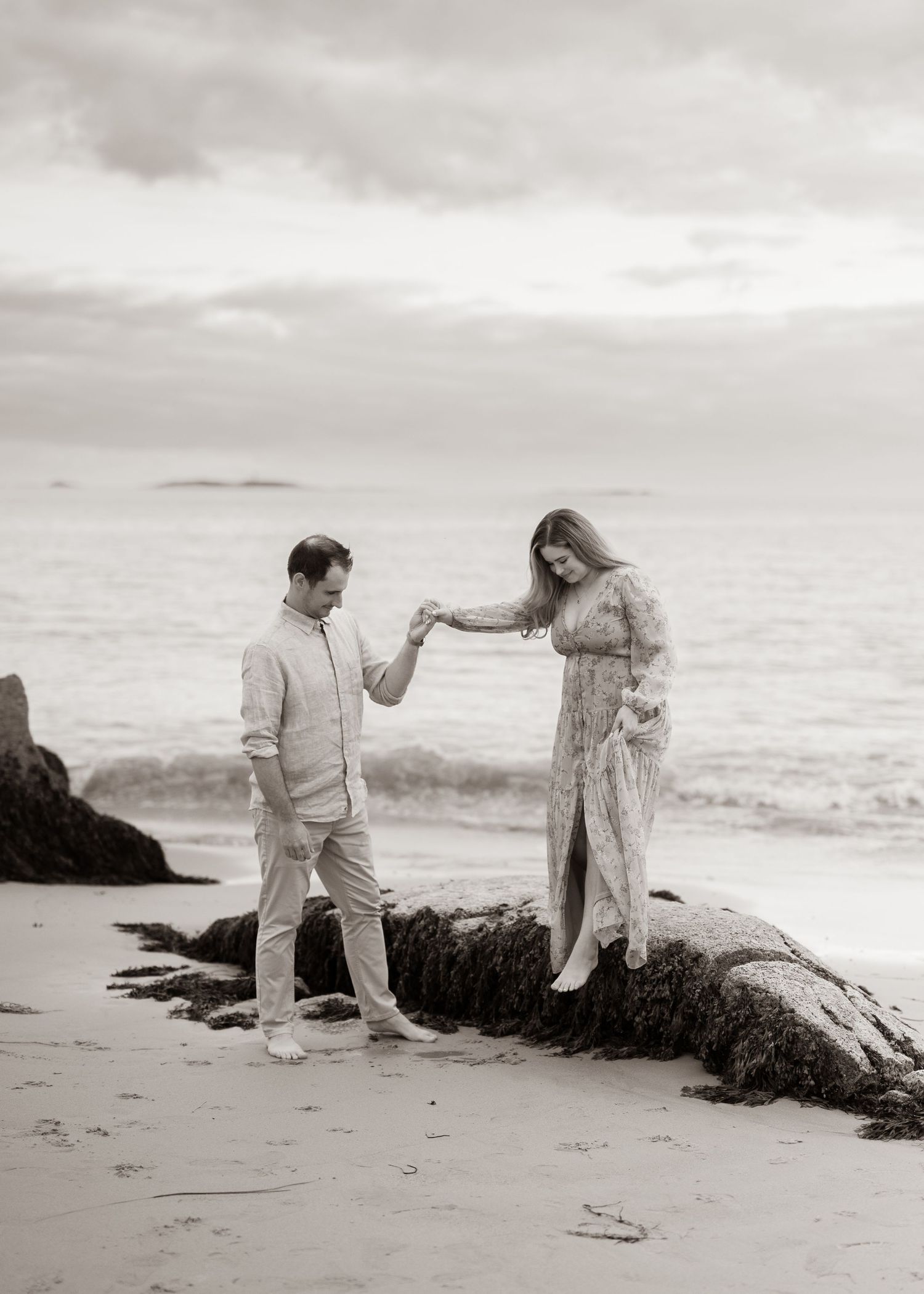 couple reaches for one another while they explore the coastal beaches on Nova Scotia together