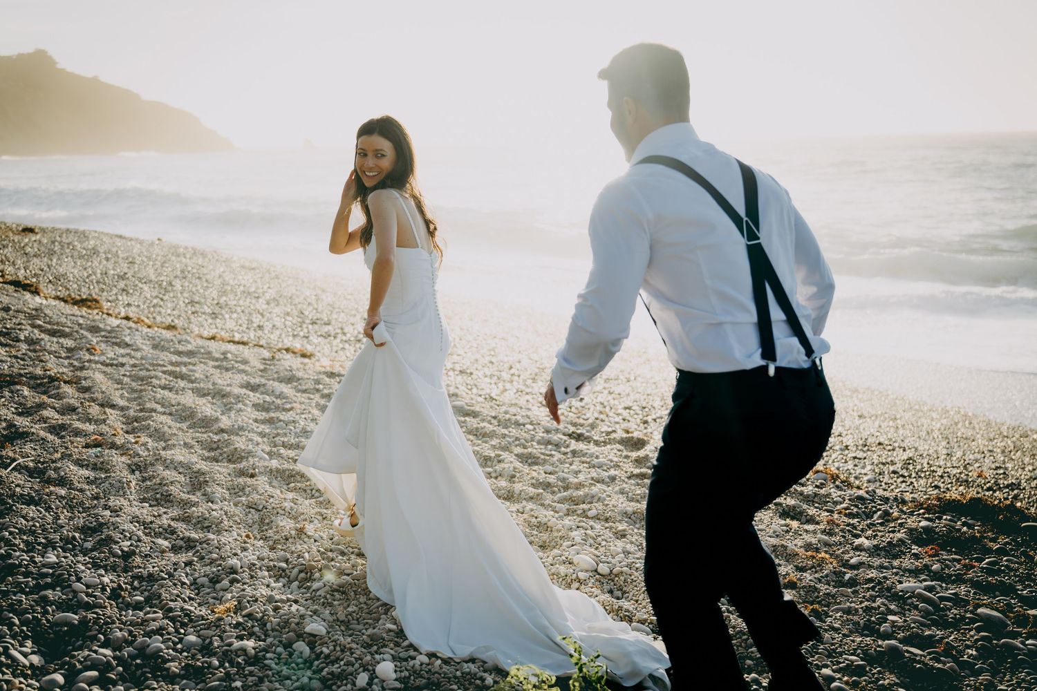 Pareja caminando por la playa durante una sesión de postboda en Asturias al atardecer