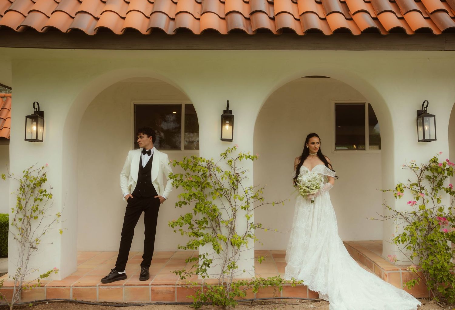 Bride in white gown and groom in tuxedo pose outside their Airbnb during their Ojai elopement.