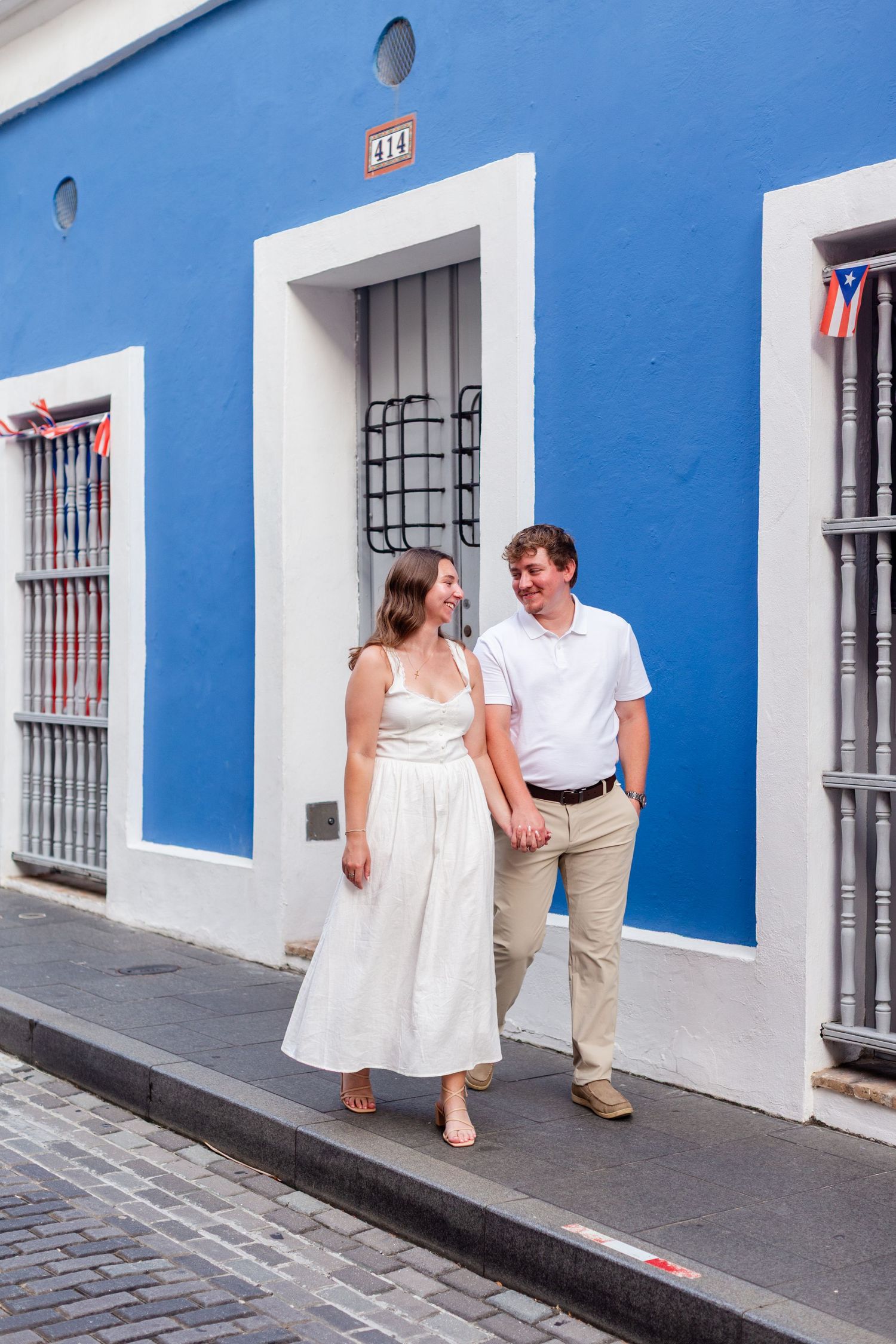 Couple walking on the sidewalk. Engagement photo session in Old San Juan, Puerto Rico.