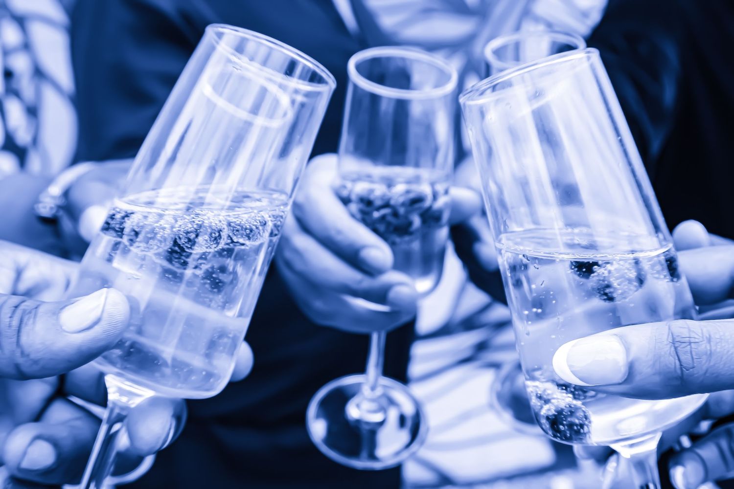People clinking champagne glasses in a celebratory toast, tinted in blue monochrome at a festive event.