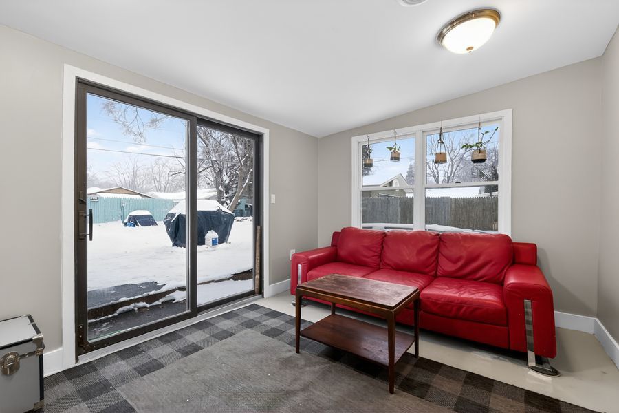 Bright living room with red sofa, sliding glass door, and snowy exterior view.