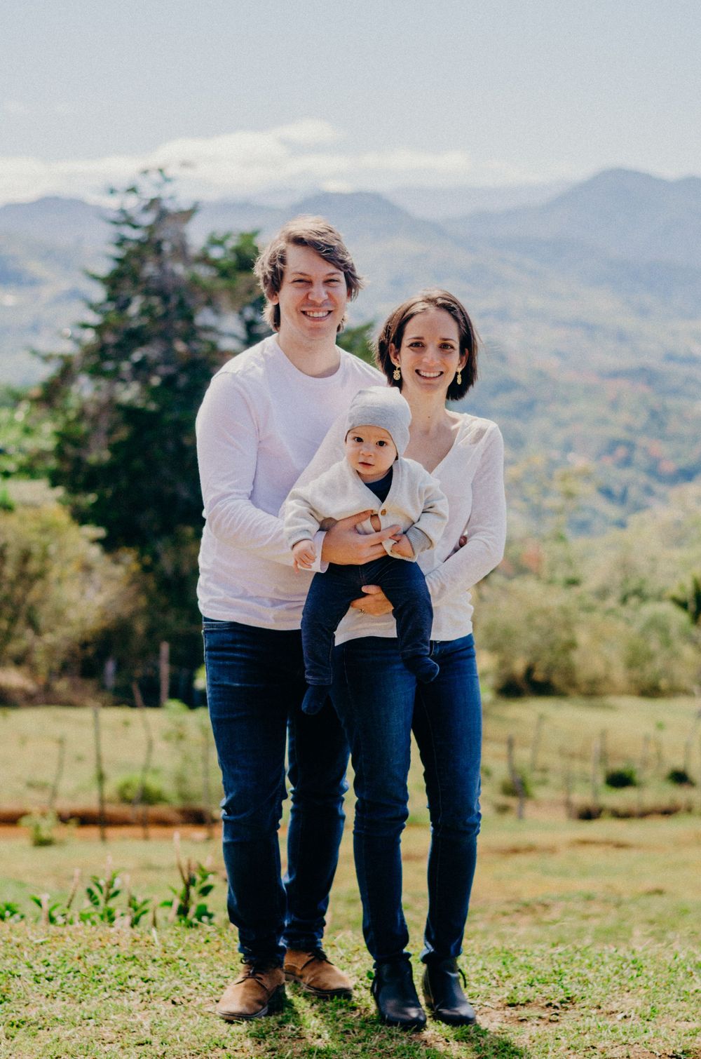 Family photo against scenic mountain backdrop on a sunny day.