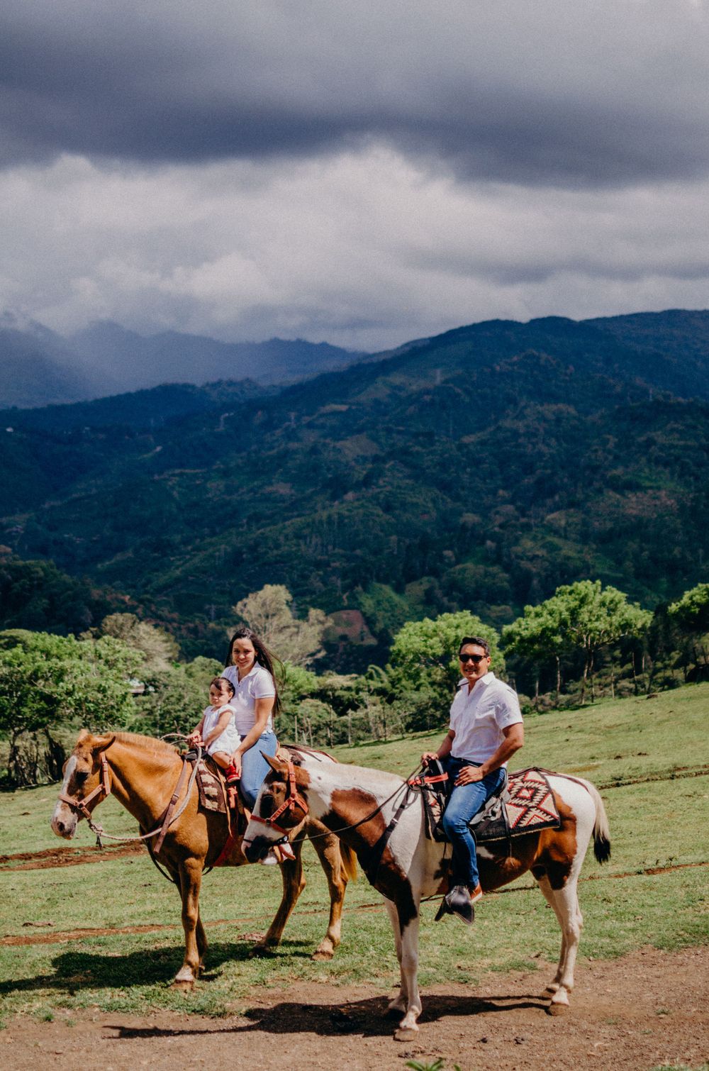 Horseback riders on trail with scenic mountain vista in background.