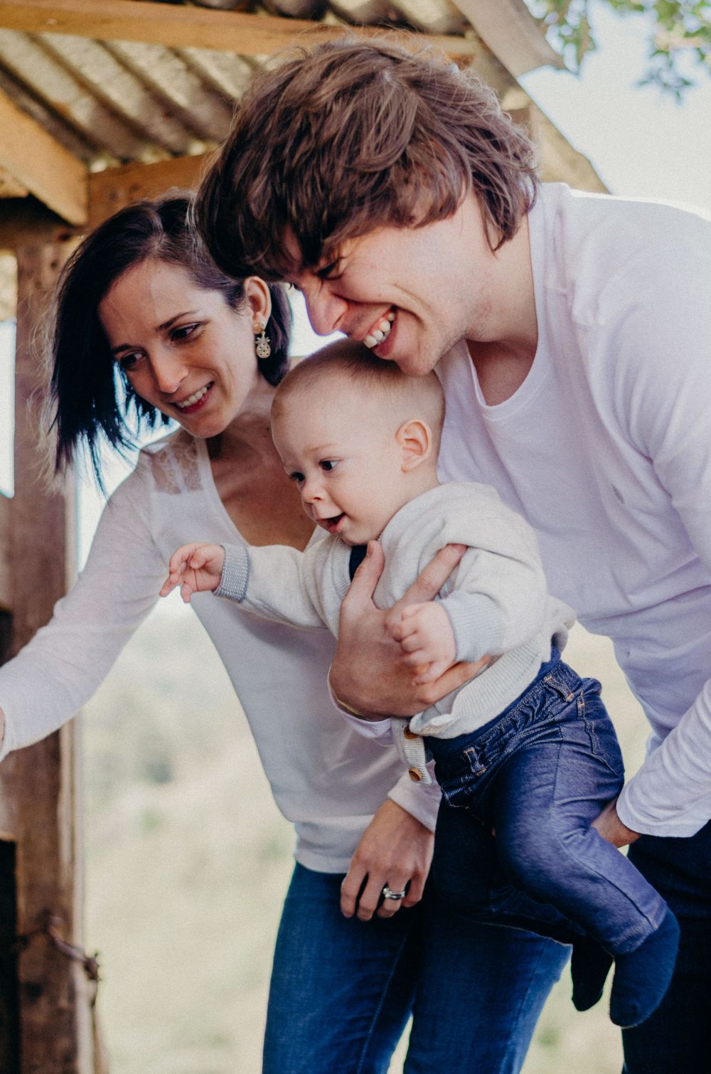 Candid family moment captured under rustic wooden awning.