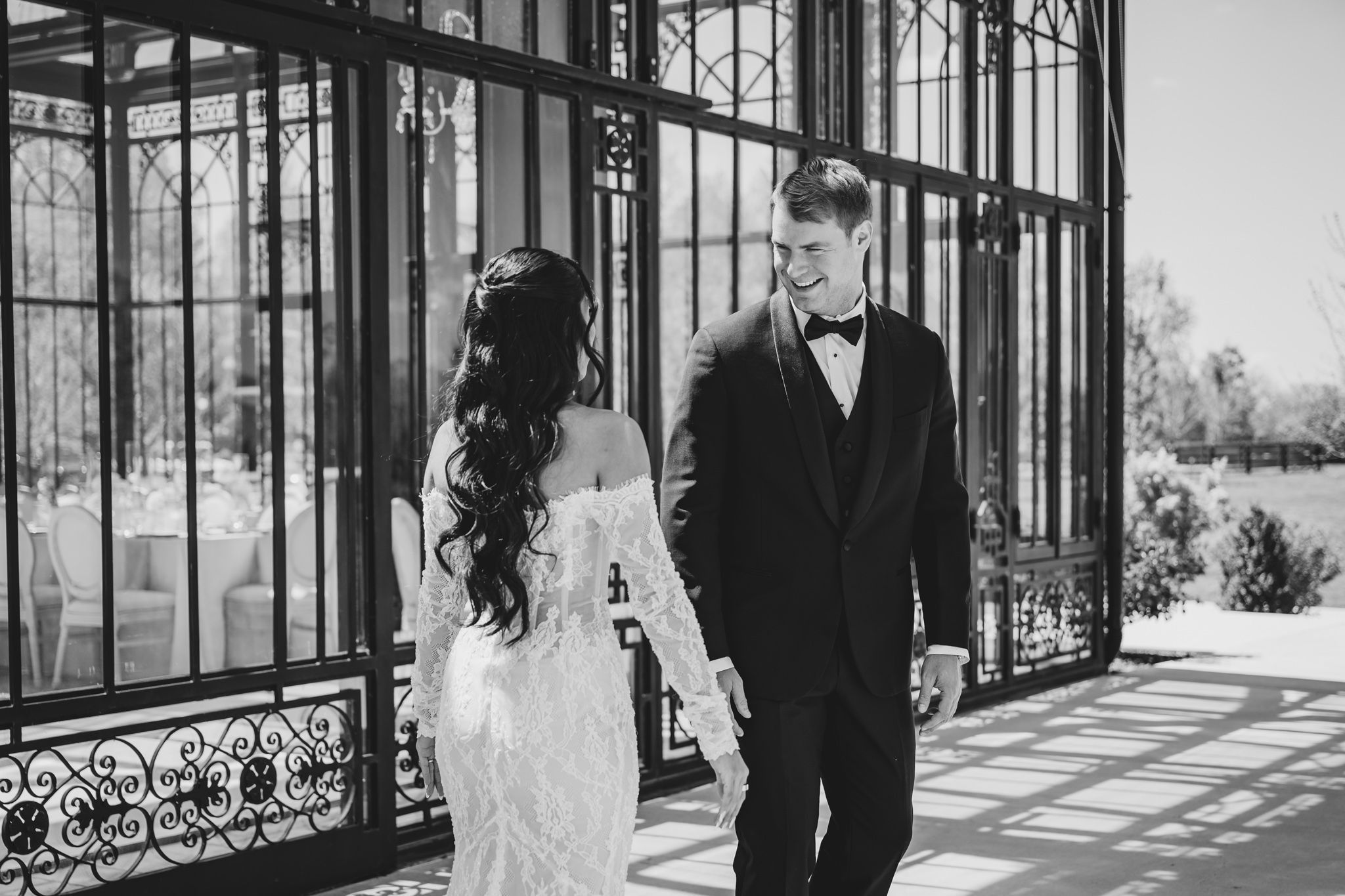 Black and white photo of bride and groom sharing a tender moment by ornate iron doors.