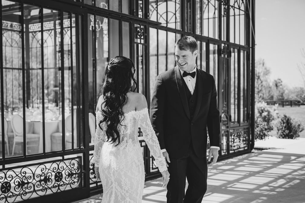 Black and white photo of bride and groom sharing a tender moment by ornate iron doors.
