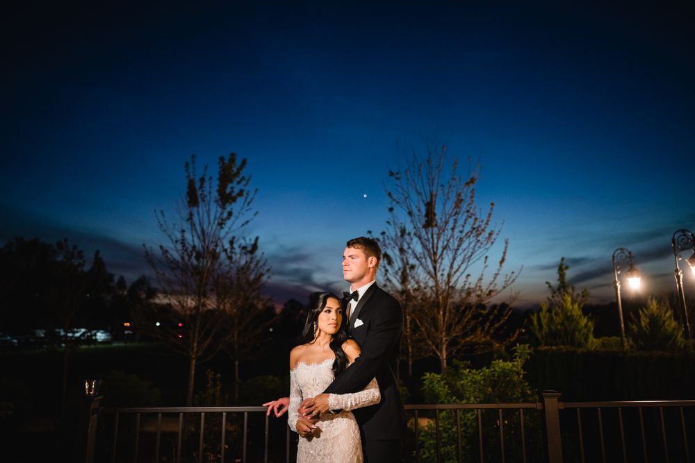 Romantic couple embracing on a balcony under a beautiful twilight sky at night.