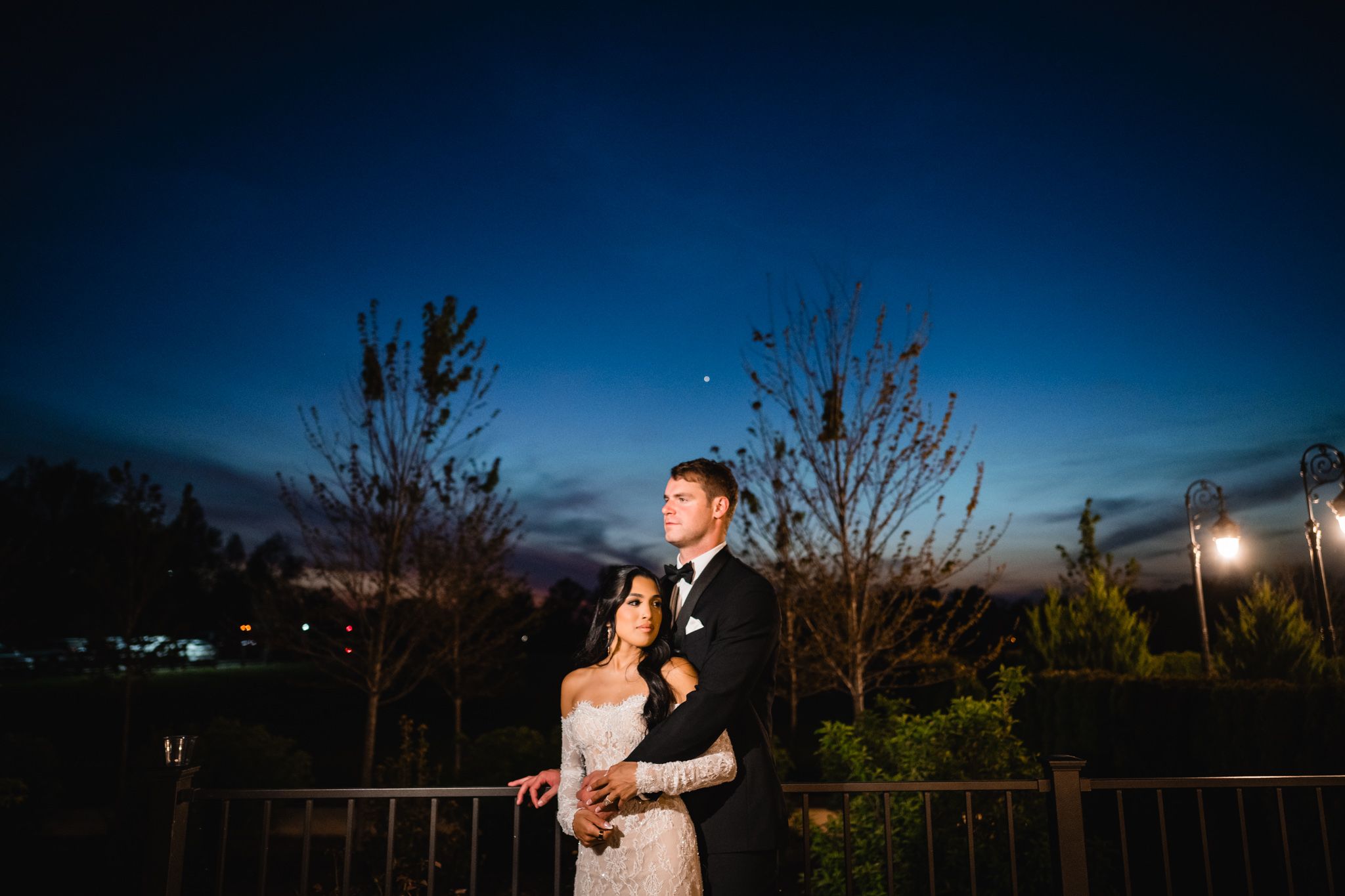 Romantic couple embracing on a balcony under a beautiful twilight sky at night.