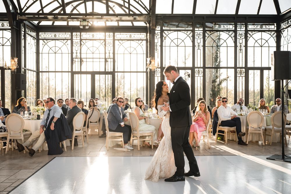 Bride and groom share their first dance in an elegant glass conservatory wedding reception.