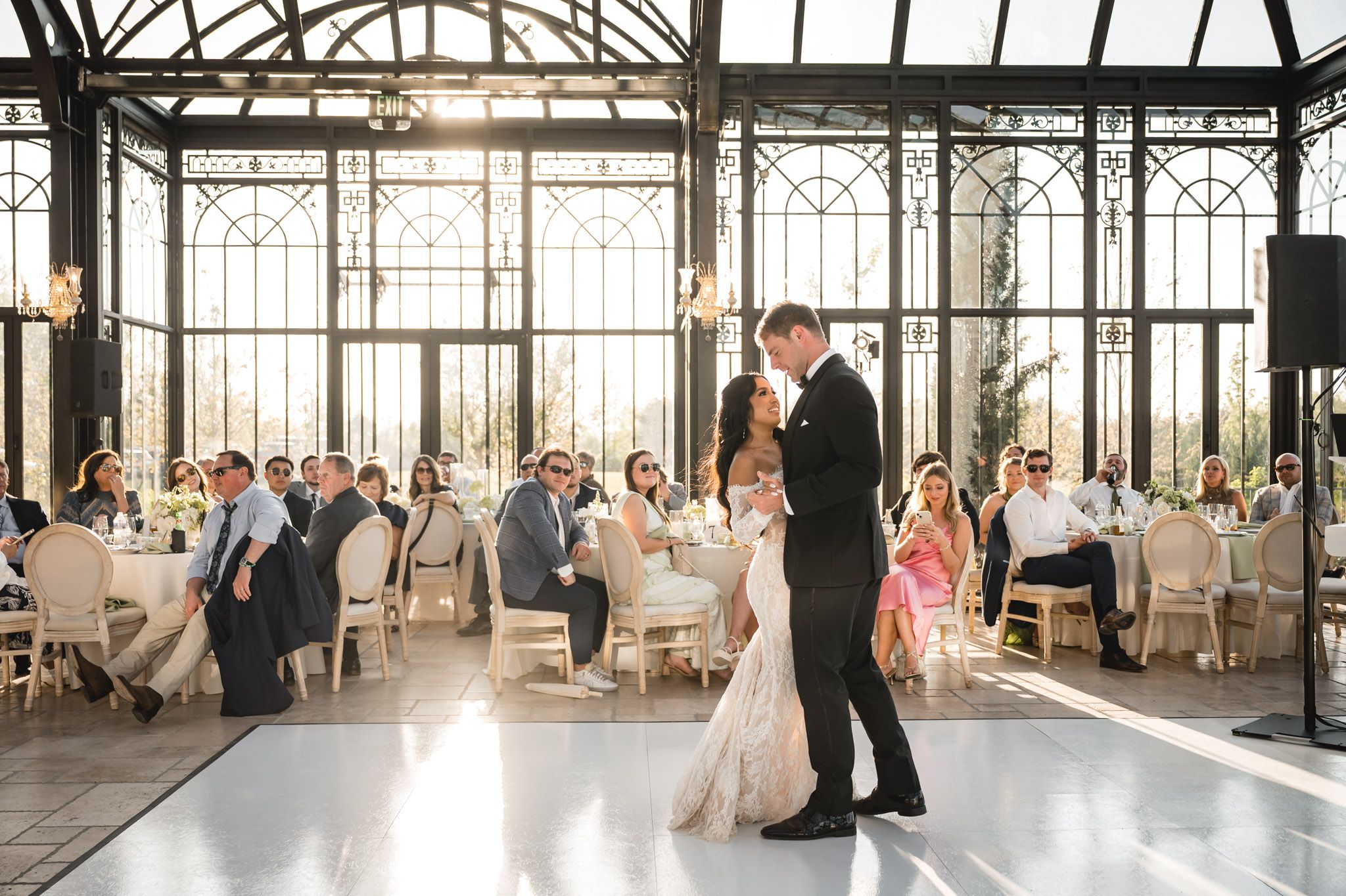 Bride and groom share their first dance in an elegant glass conservatory wedding reception.