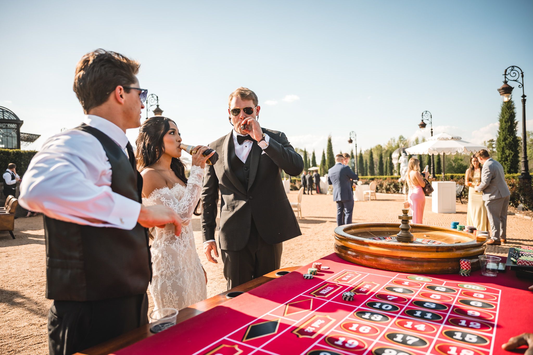 Bride and groom play roulette at a casino-themed outdoor wedding cocktail hour.