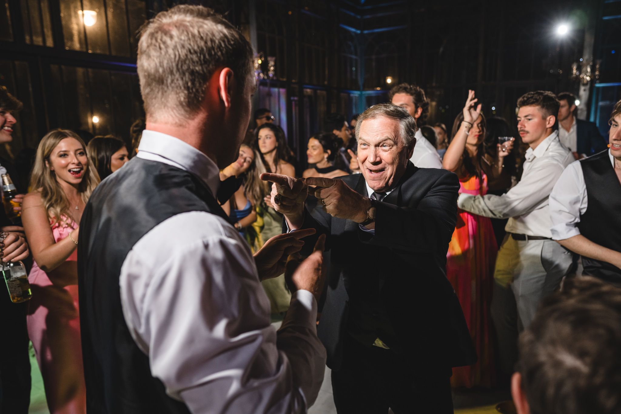 Energetic wedding reception dance floor with guests celebrating and dancing with the groom at a lively party.