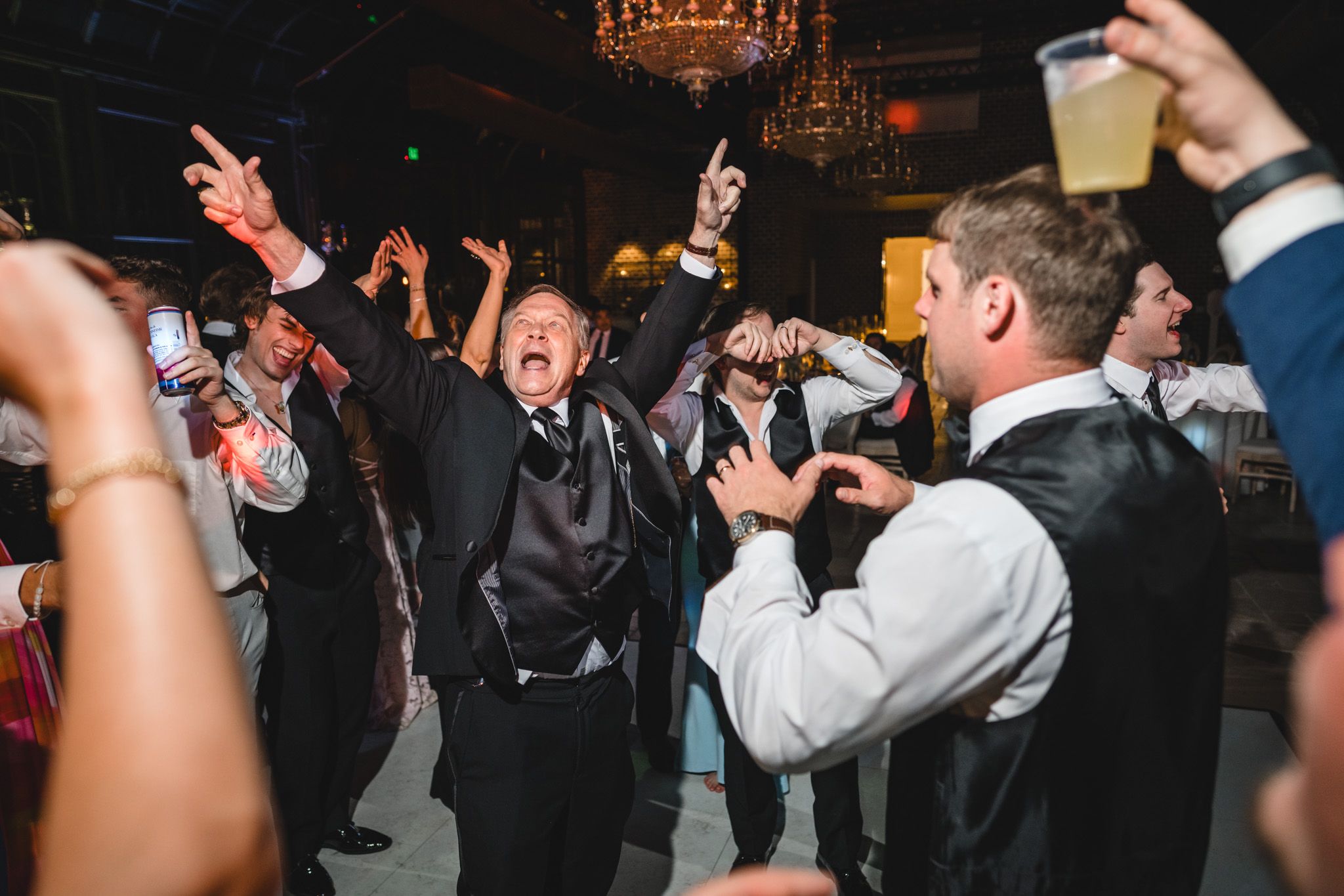 Energetic wedding guests celebrating on the dance floor at a lively reception party.
