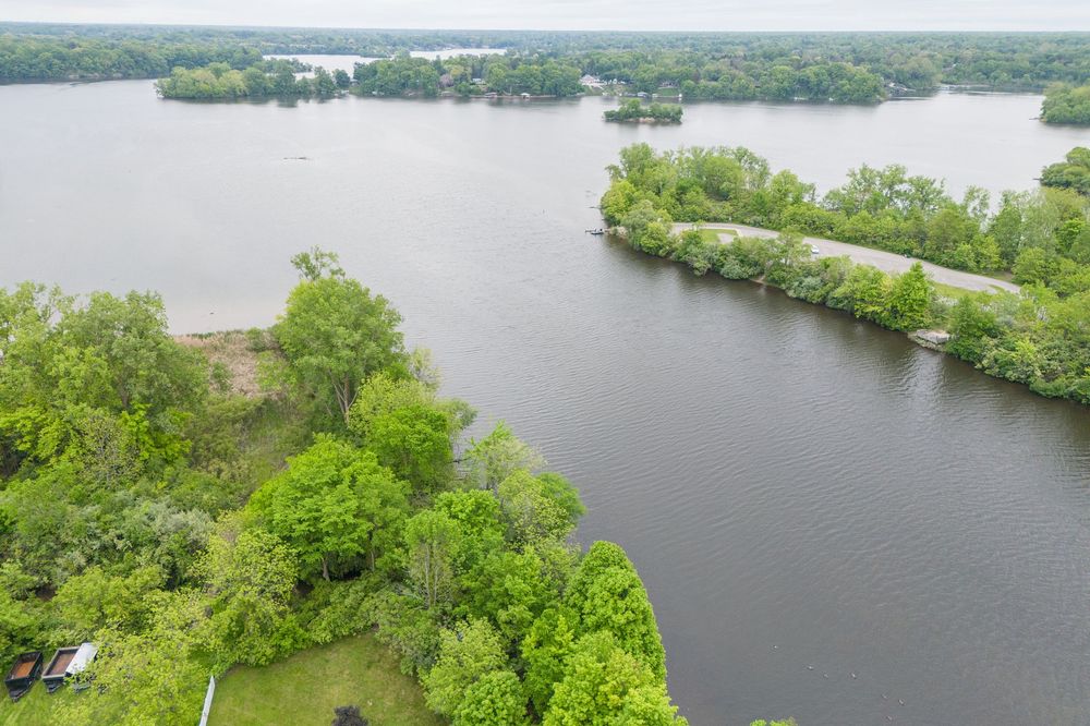 Aerial view of a serene river surrounded by lush green trees and islands under an overcast sky.