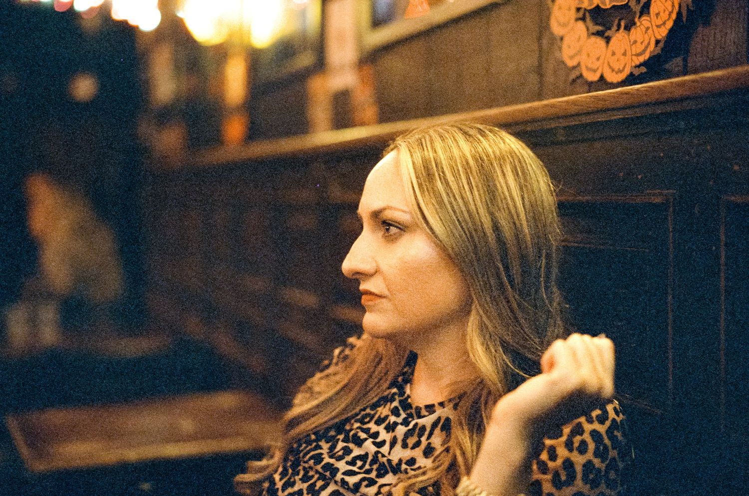 Side profile portrait in warm lighting wearing a leopard print top.
