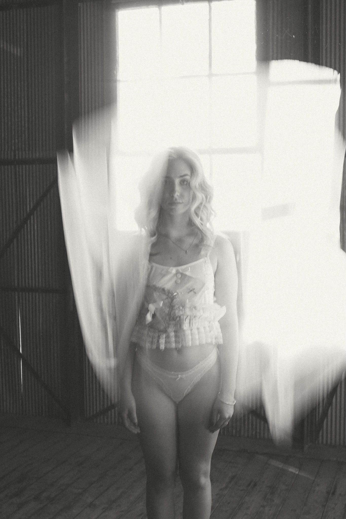 Black and white ghostly image of woman in hall staring at camera and tulle falling in front of them