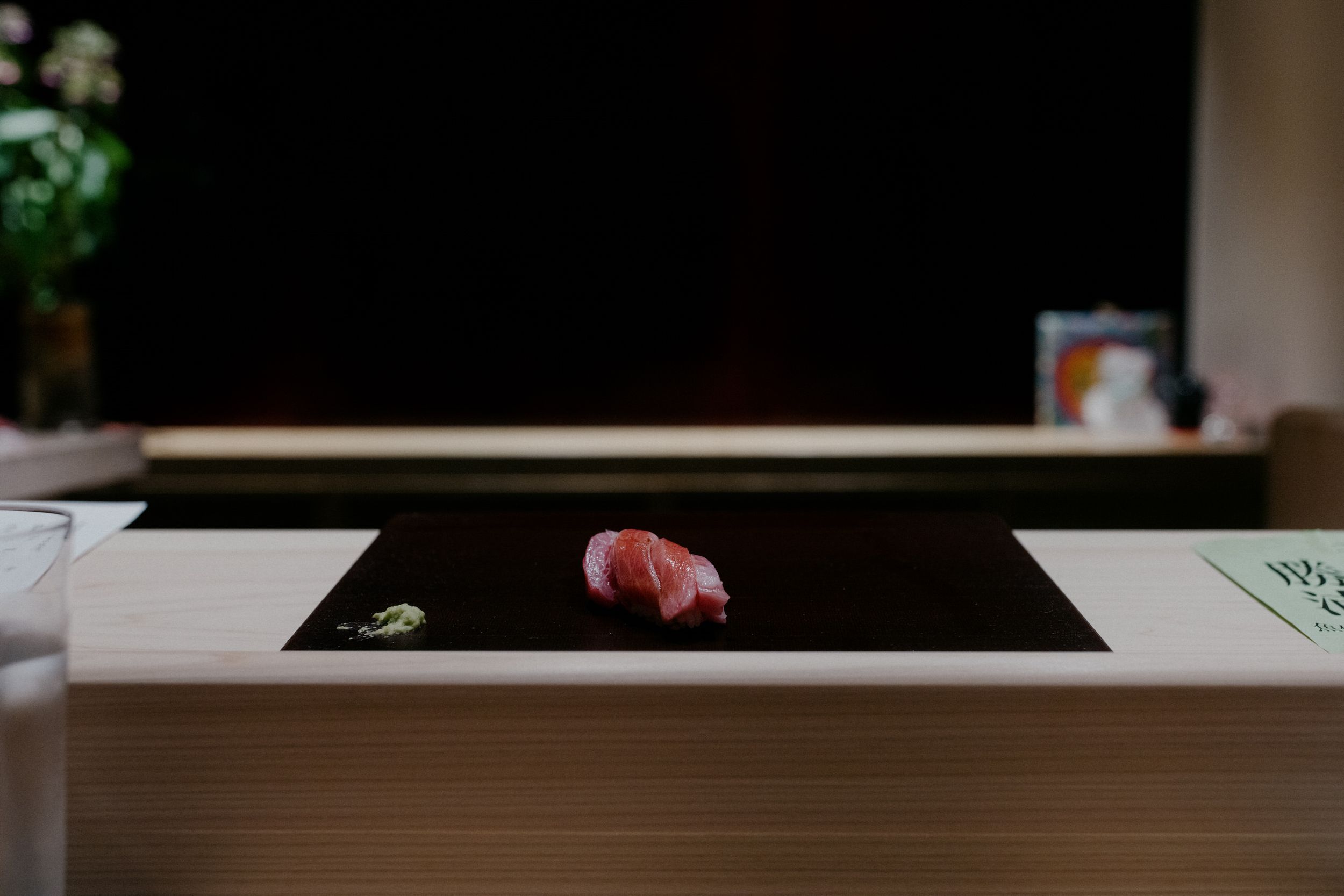 Single piece of sushi placed on black serving board.