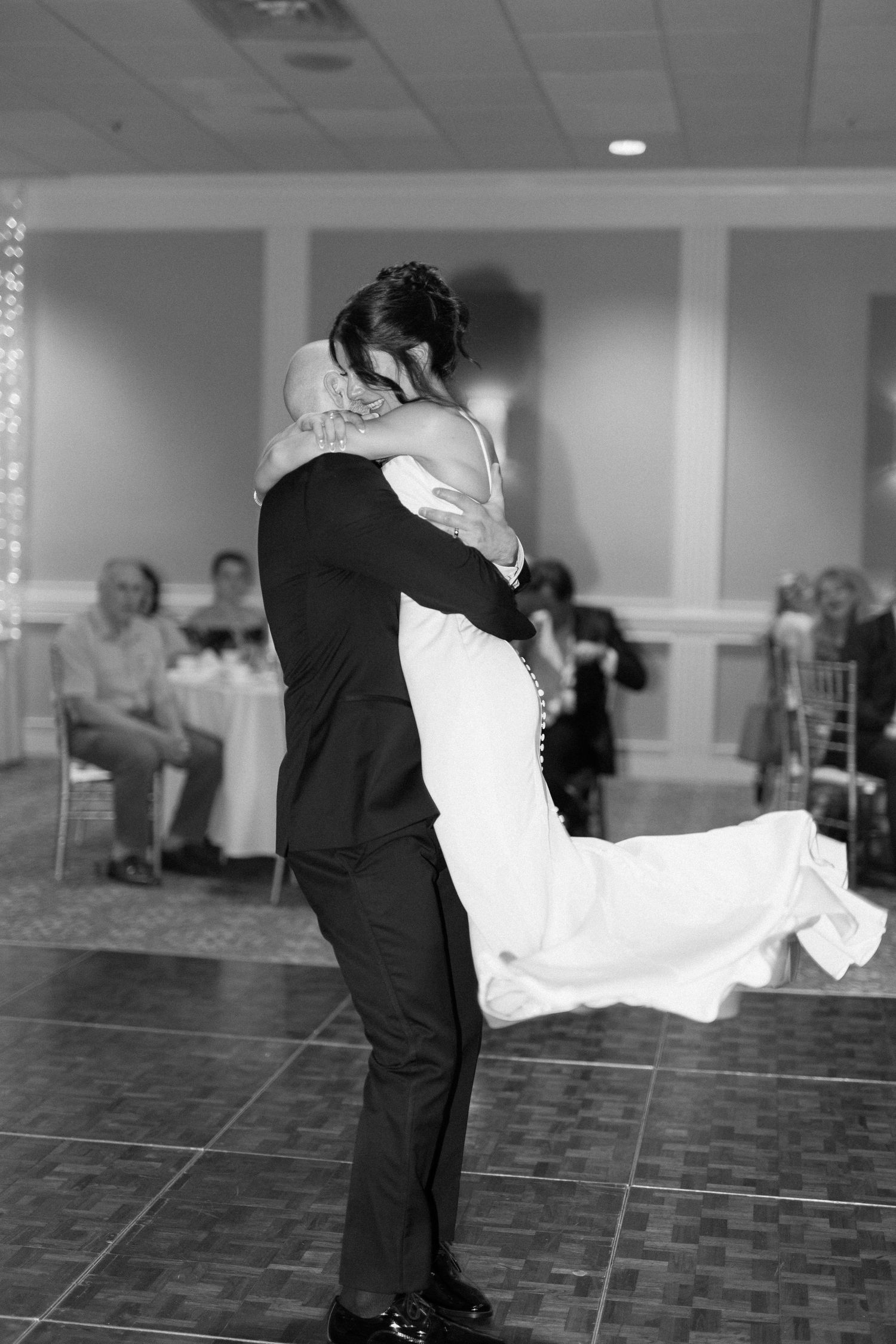 A couple shares their first dance at a wedding reception, with the bride's dress flowing gracefully.