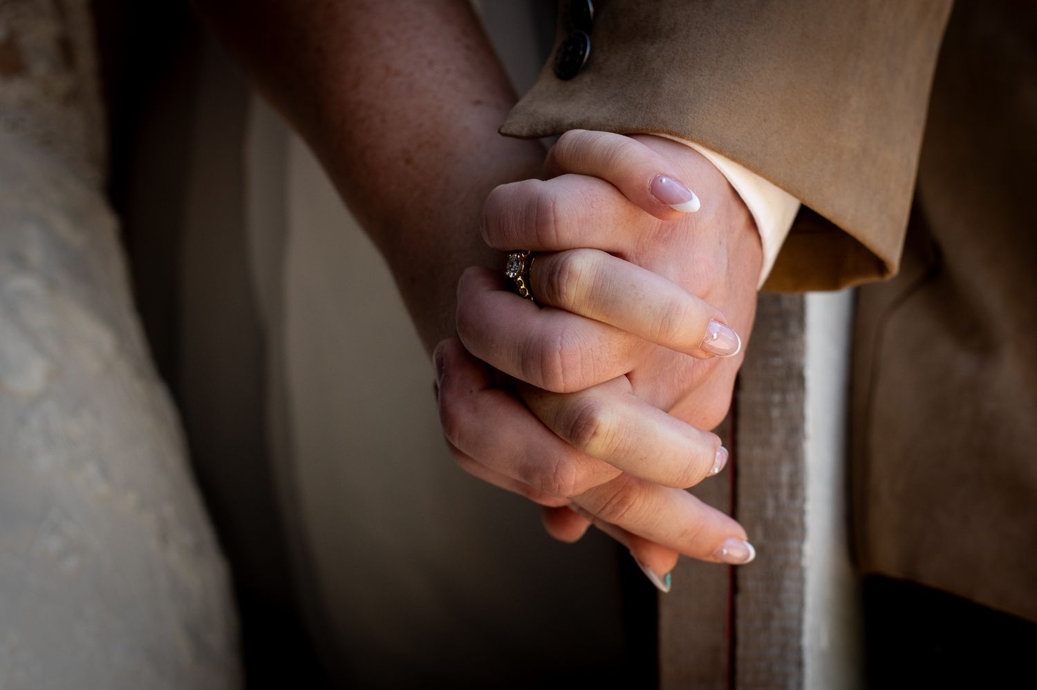 Close-up detail shot of clasped hands with wedding rings.