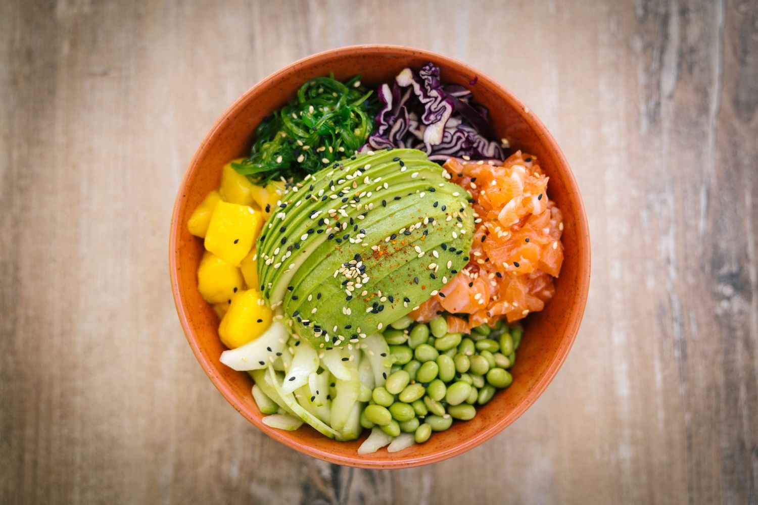 Colorful poke bowl with avocado, edamame, mango and fresh vegetables.
