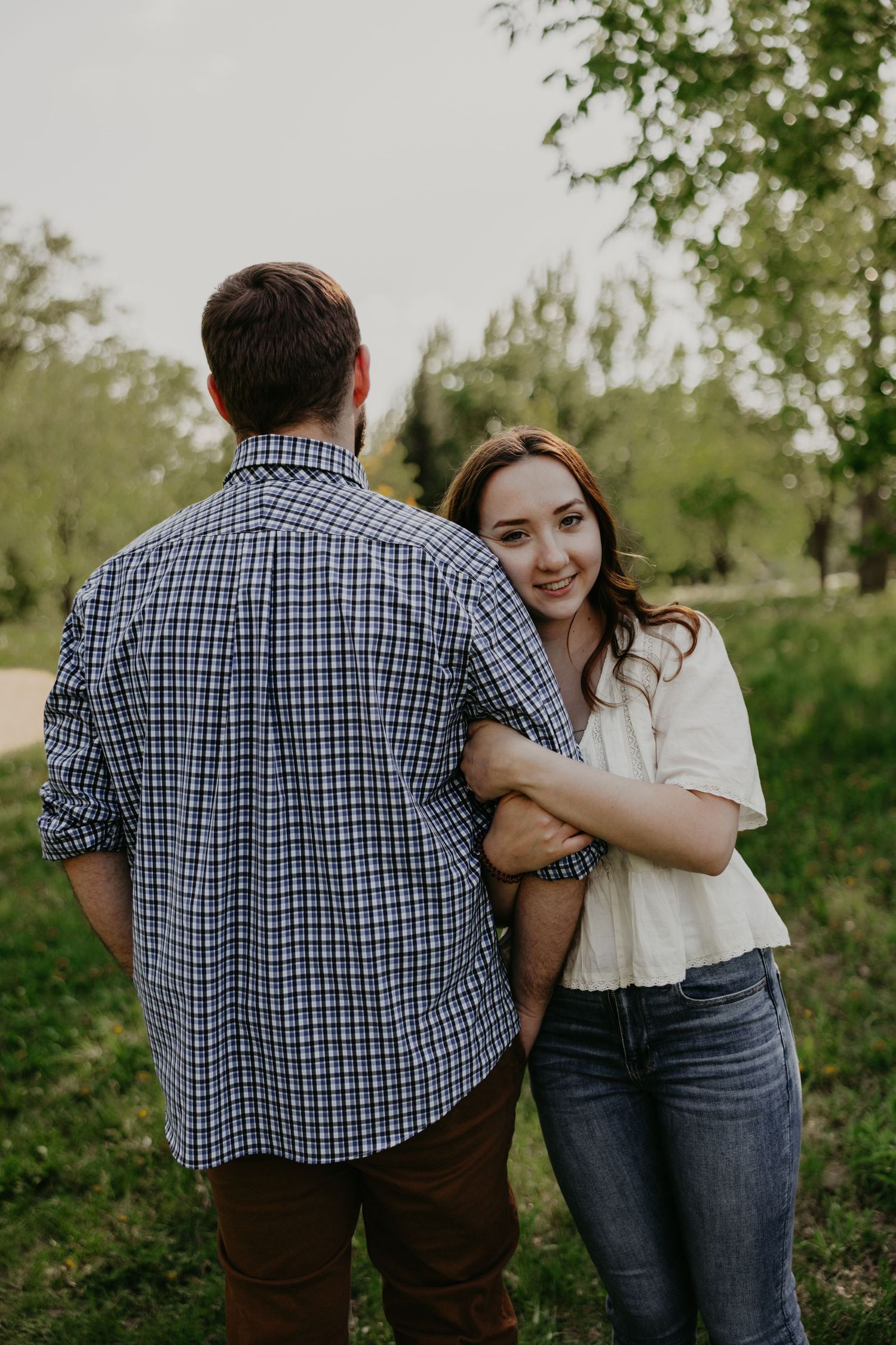 Casual outdoor couple's portrait session among green trees and foliage.