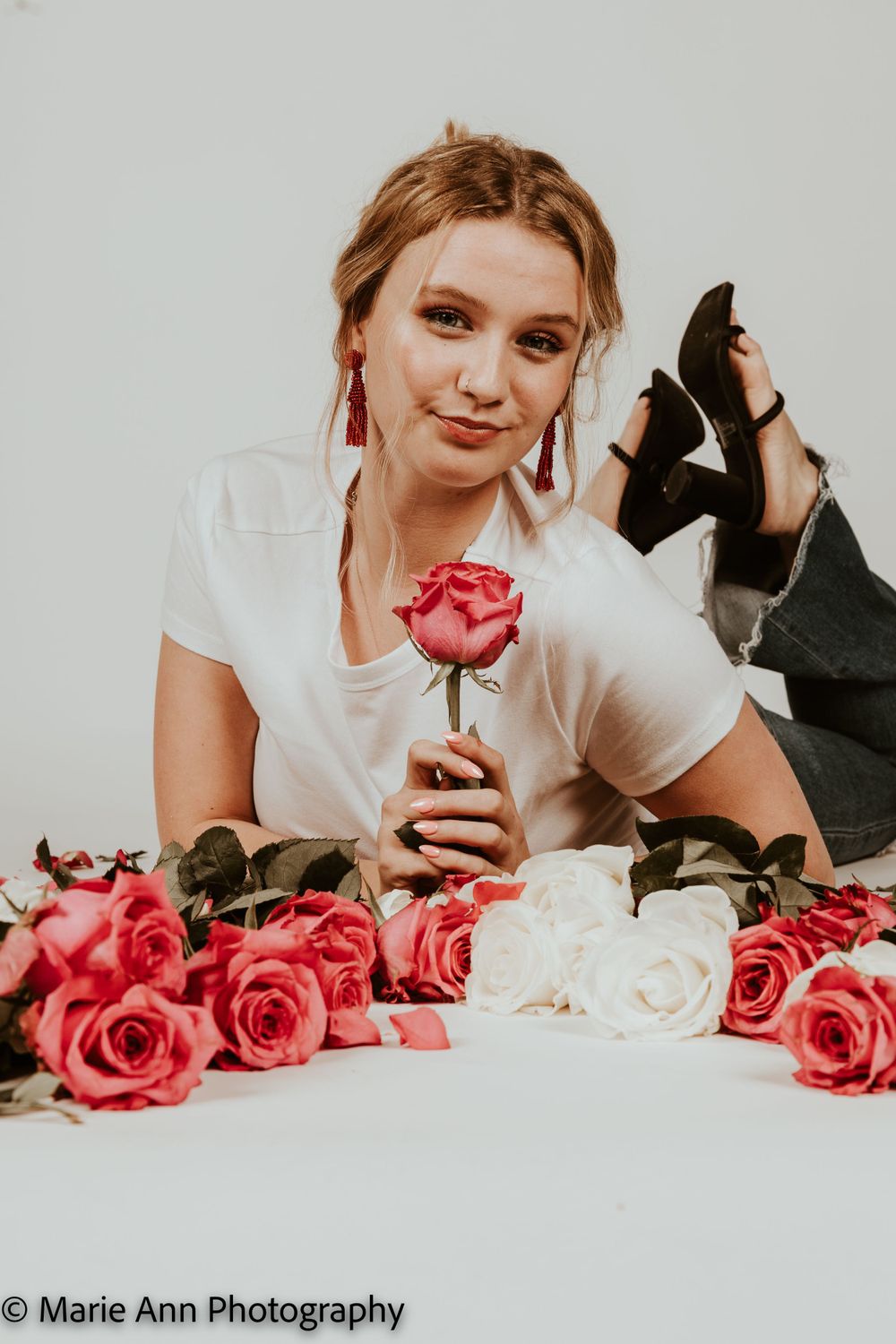 Young woman posing with pink and white roses in a studio photo shoot by Marie Ann Photography.