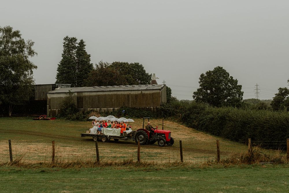 Outdoor wedding venue setup with white tent and red tractor visible in rural countryside setting.