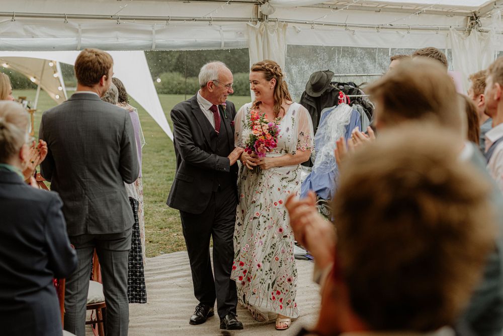 Wedding celebration inside a white tent with guests mingling and socializing.