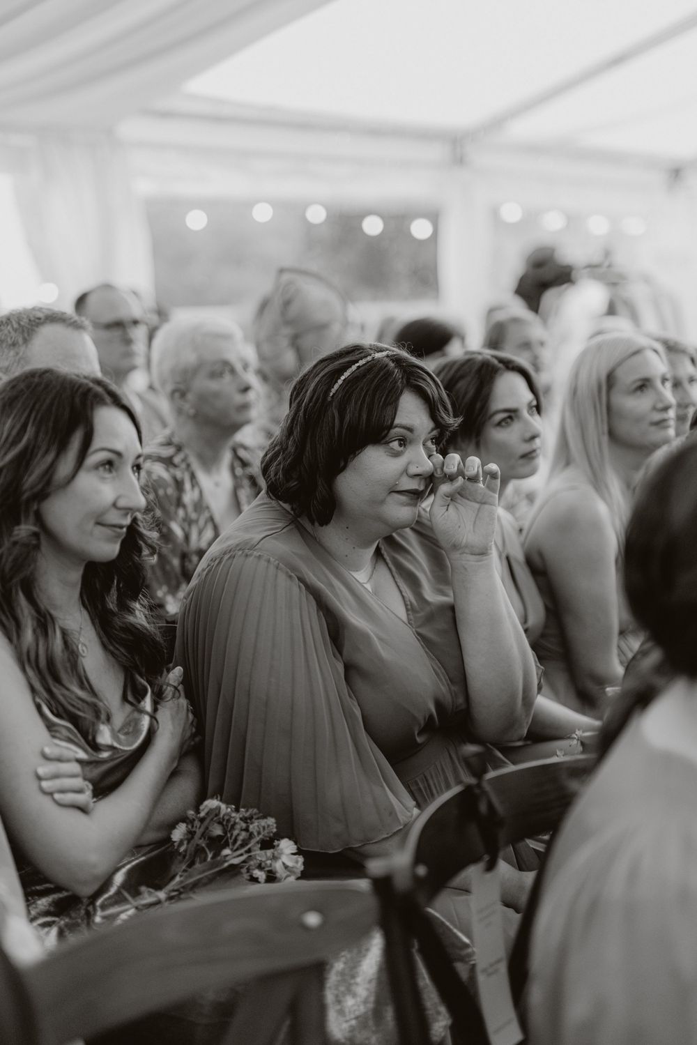 Black and white candid shot of wedding guests enjoying the reception under string lights.